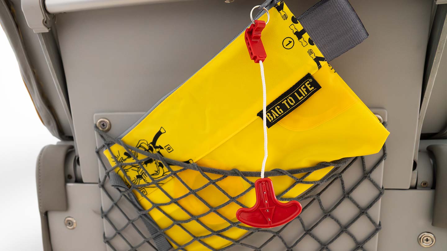 Yellow cable bag made from recycled airplane life vest in aircraft seat pocket, gift for travelers